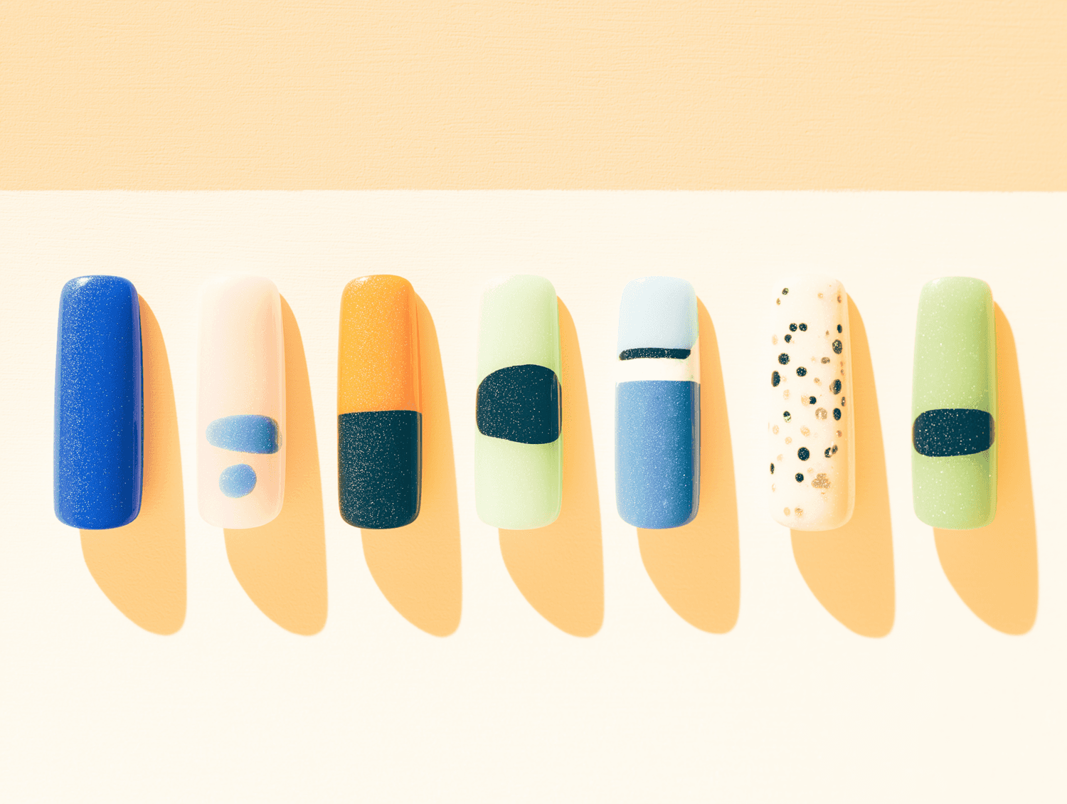 Muestrario de uñas con diseños geométricos en azul, verde y naranja